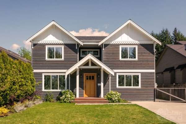TrueVue 15 1 A modern two-story house with dark exterior siding and large reflective windows, showcasing the benefits of TrueVue window film.