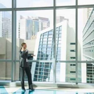 Solar Gard Sentinel Plus Series: Image is showing a window with buildings visible outside and a business woman talking on the phone standing near the window.